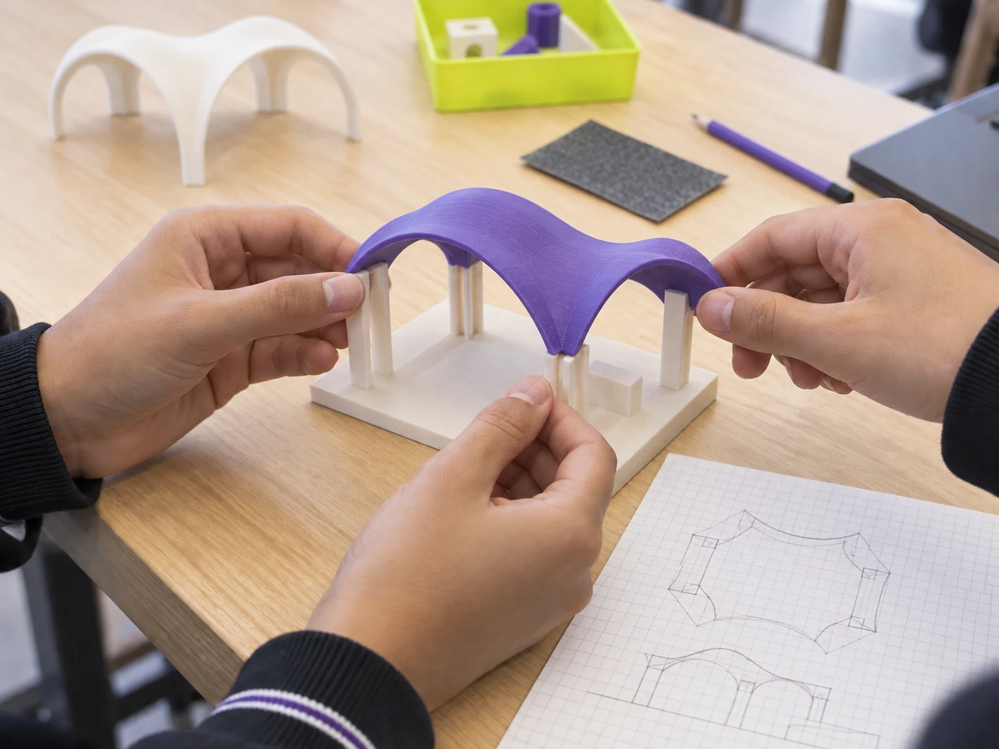 Detalle de manos construyendo una maqueta arquitectónica impresa en 3D.